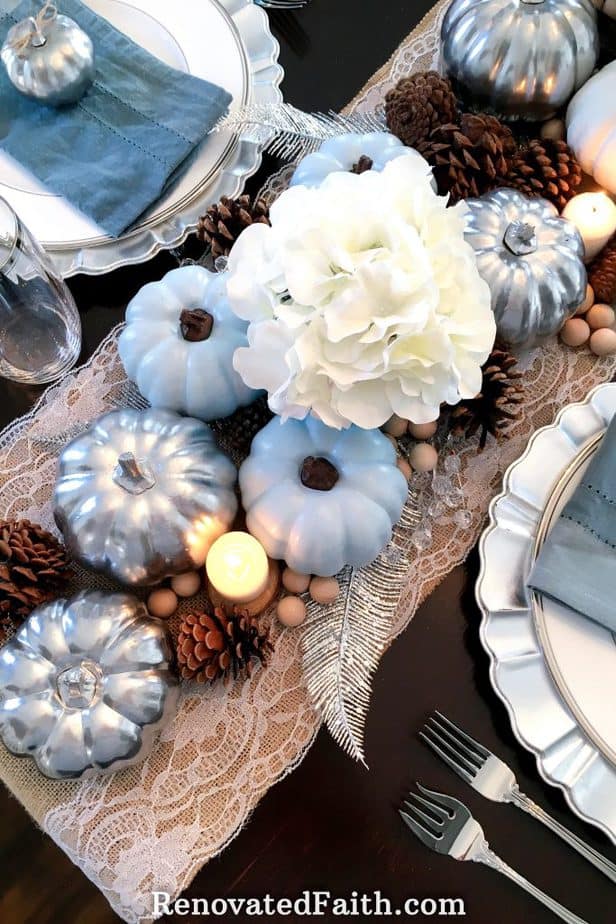 Thanksgiving Tablescape with Blue Pumpkins – Want an elegant centerpiece on a budget? Paint dollar store pumpkins in blue and silver for a traditional tablescape with a modern flair. The use of natural pine cones and burlap add some vintage style to contrast the glam of the silver pumpkins. This easy fall décor shows that simple and beautiful centerpieces don’t have to be expensive. #fall #thanksgiving #centerpiece #pumpkins #bluepumpkins #dollarstore 