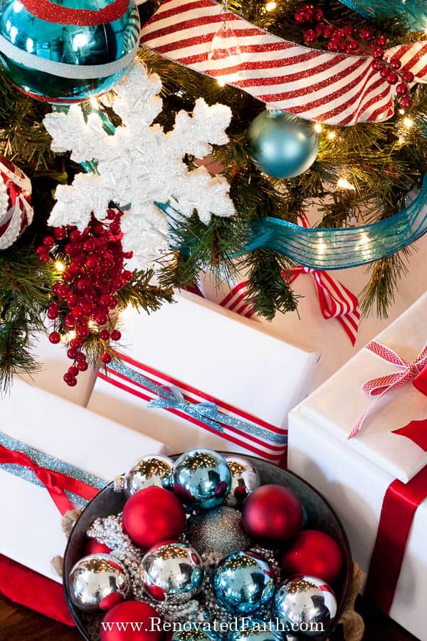 close up of ornaments on tree and presents undertneath