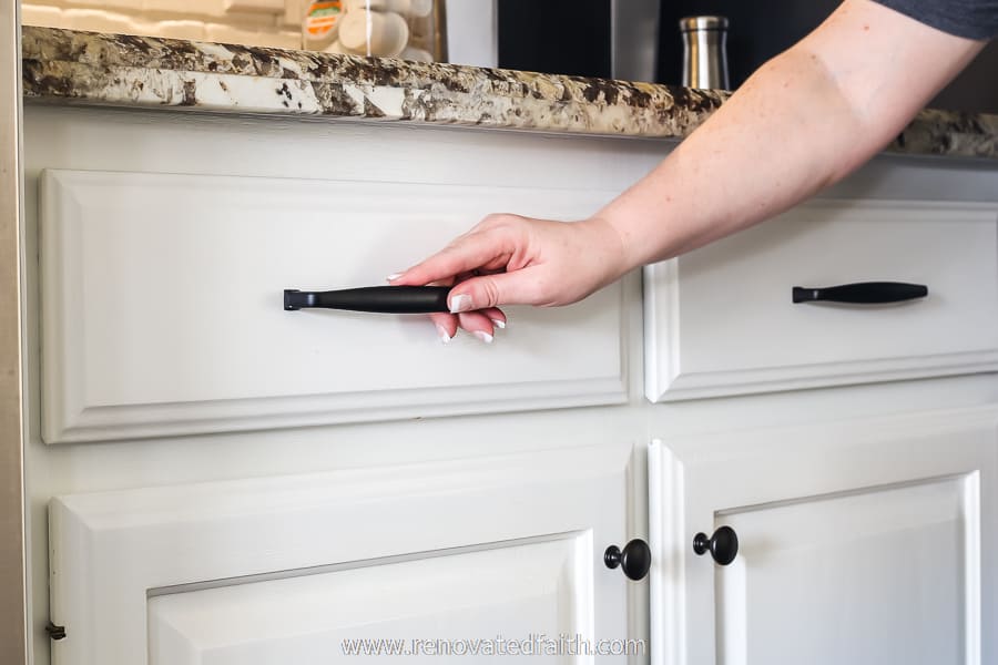 newly installed cabinet hardware with woman's hand