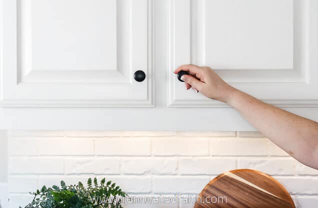 woman's hand on kitchen cabinet hardware