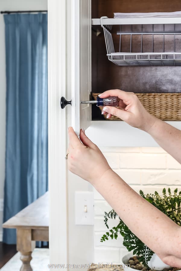 hands installing knobs on cabinets