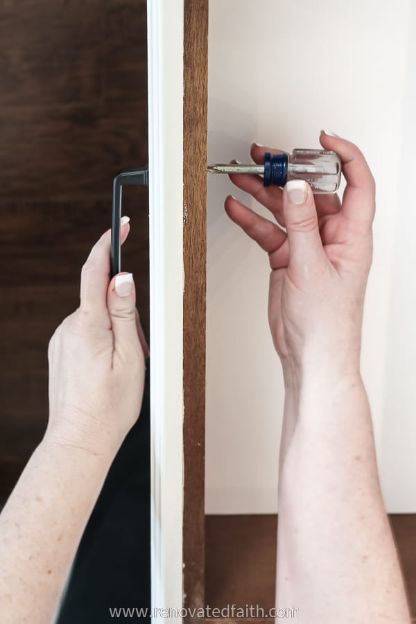 woman's hands installing cabinet handles