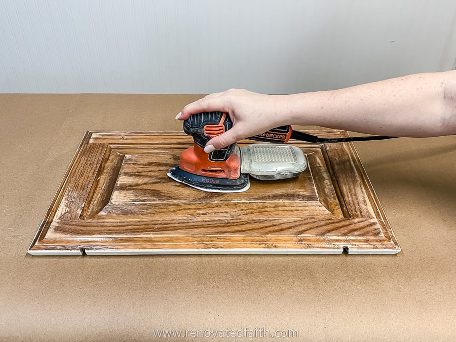 woman's hand on sander on cabinet door