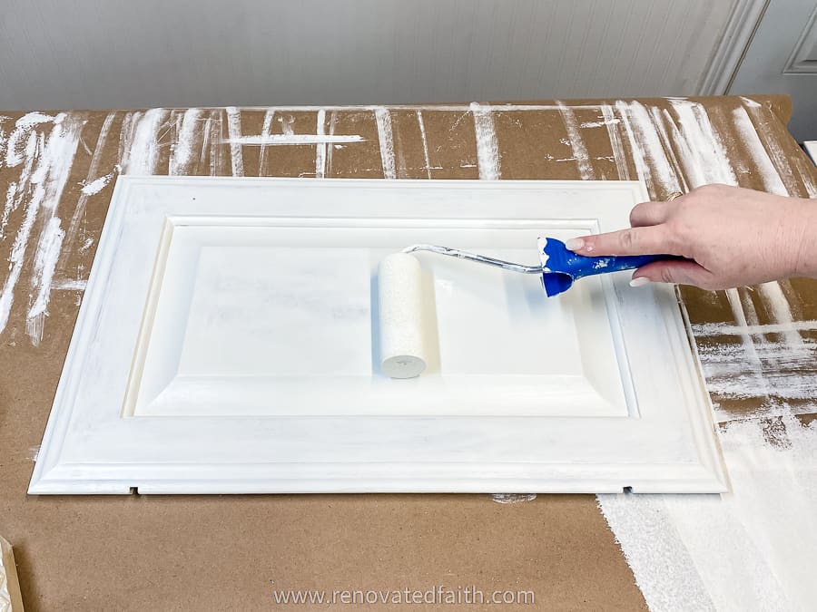 rolling white paint on a cabinet door