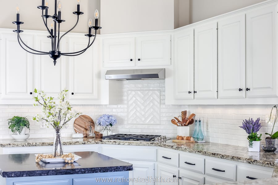 close up of white kitchen cabinets and white brick backsplash