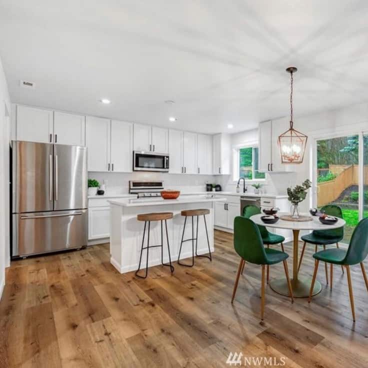 extra white kitchen cabinets  and green chairs around table