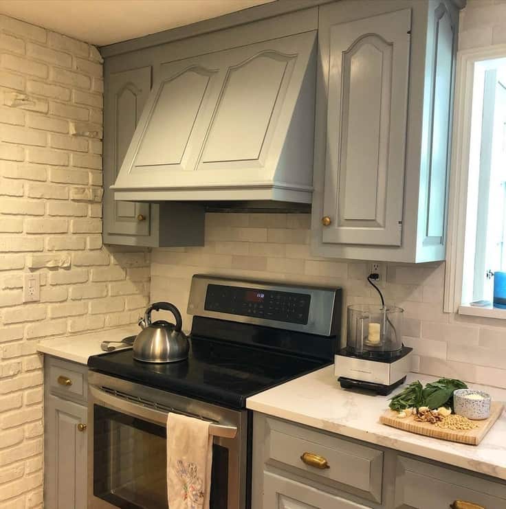 small kitchen with blue gray cabinets and white brick