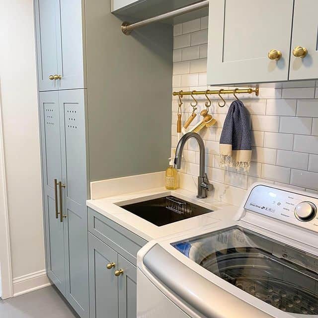 laundry room with blue-gray cabinets and gold hardware