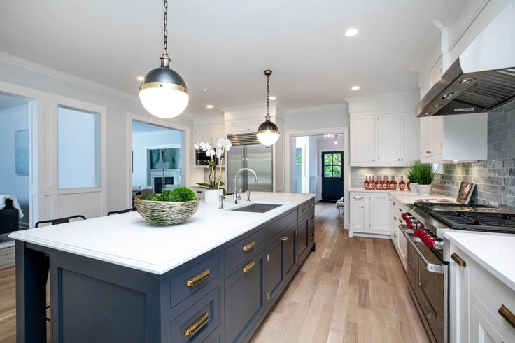 https://renovatedfaith.com/wp-content/uploads/2022/12/white-cabinets-in-kitchen-with-blue-walls-and-navy-island.jpg