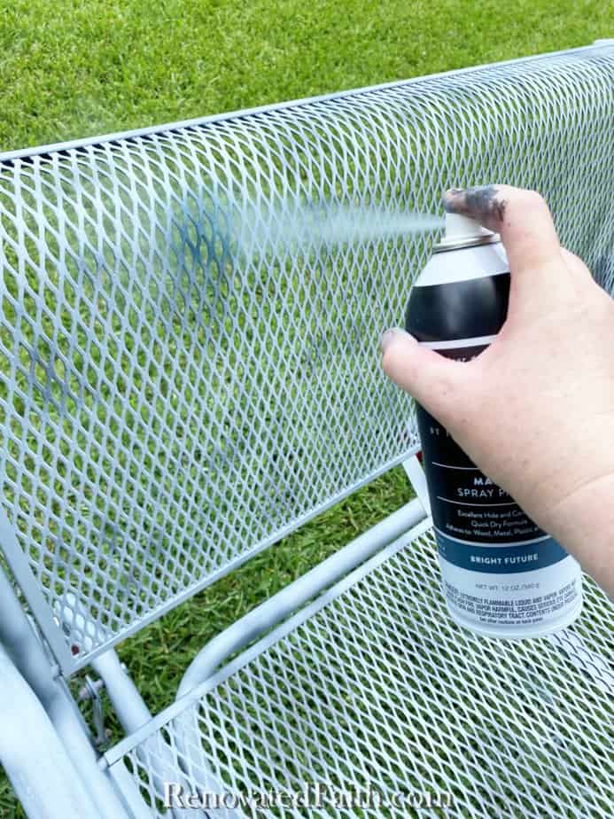 spray painting a wrought iron glider with blue spray paint